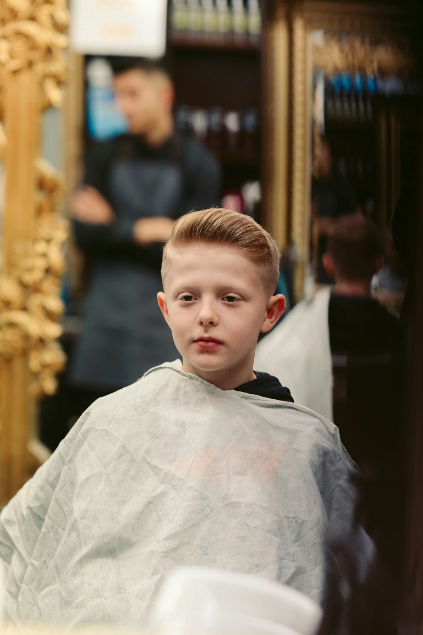 a young boy getting his hair cut at a barber shop