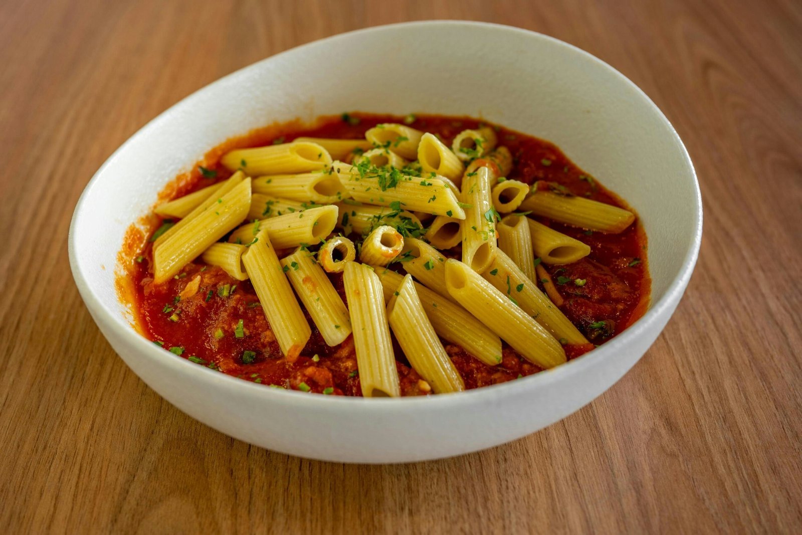 A white bowl filled with pasta and sauce